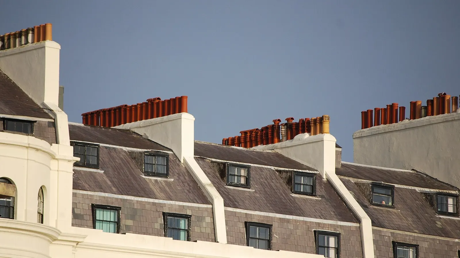 Row of Georgian terraced houses with slate roofs and brick chimney stacks topped with red clay chimney pots