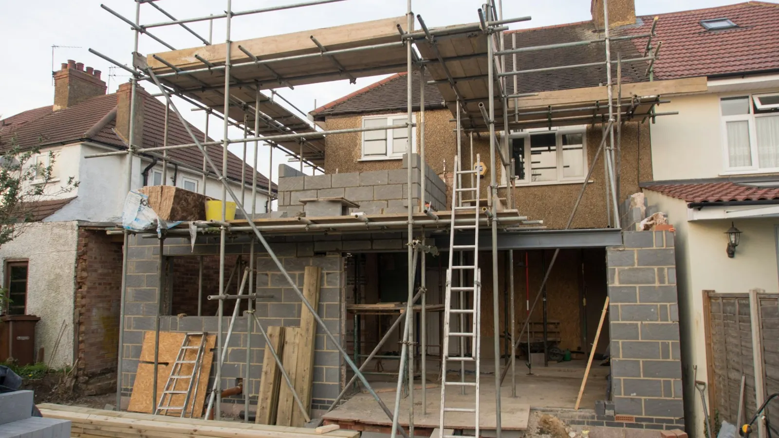 British brick house wrapped in scaffolding during a two-storey extension build