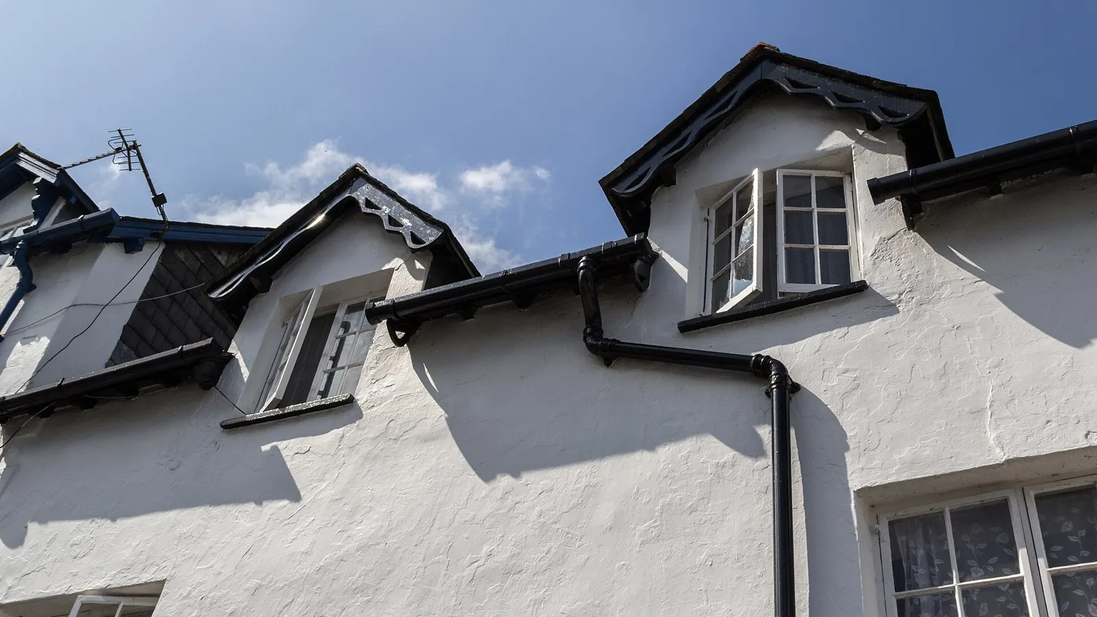 White-painted cottages with slate roofs, dormer windows and black gutters and downpipes in Devon