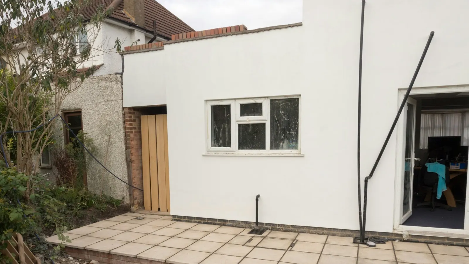 Rendered single-storey rear extension with a flat roof and brick parapet