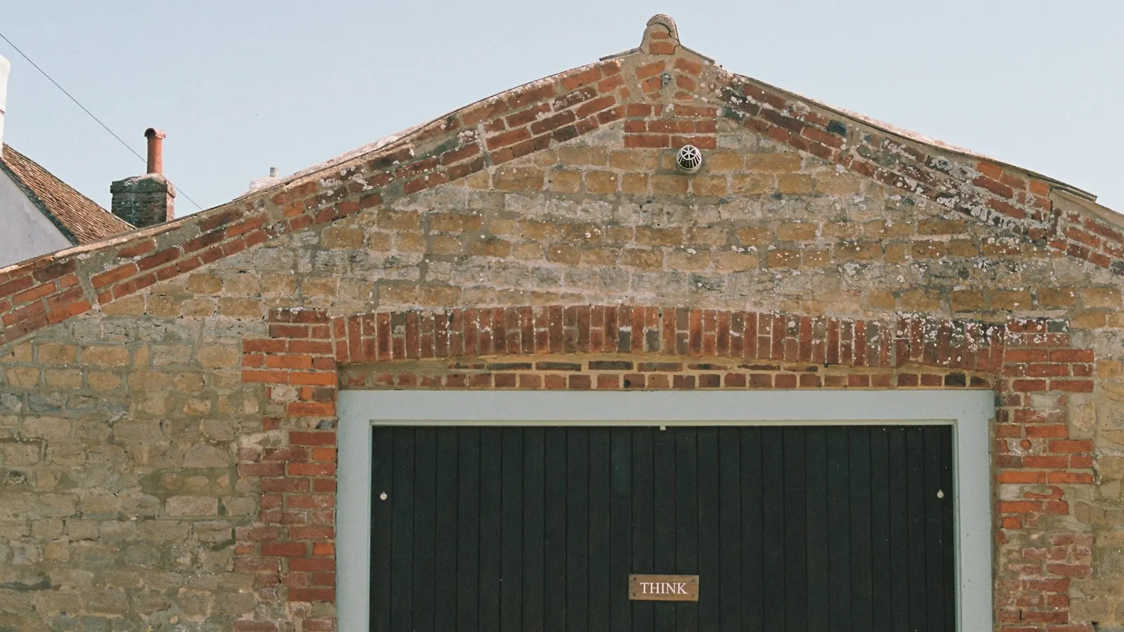 Brick garage with a pitched gable front and a dark garage door