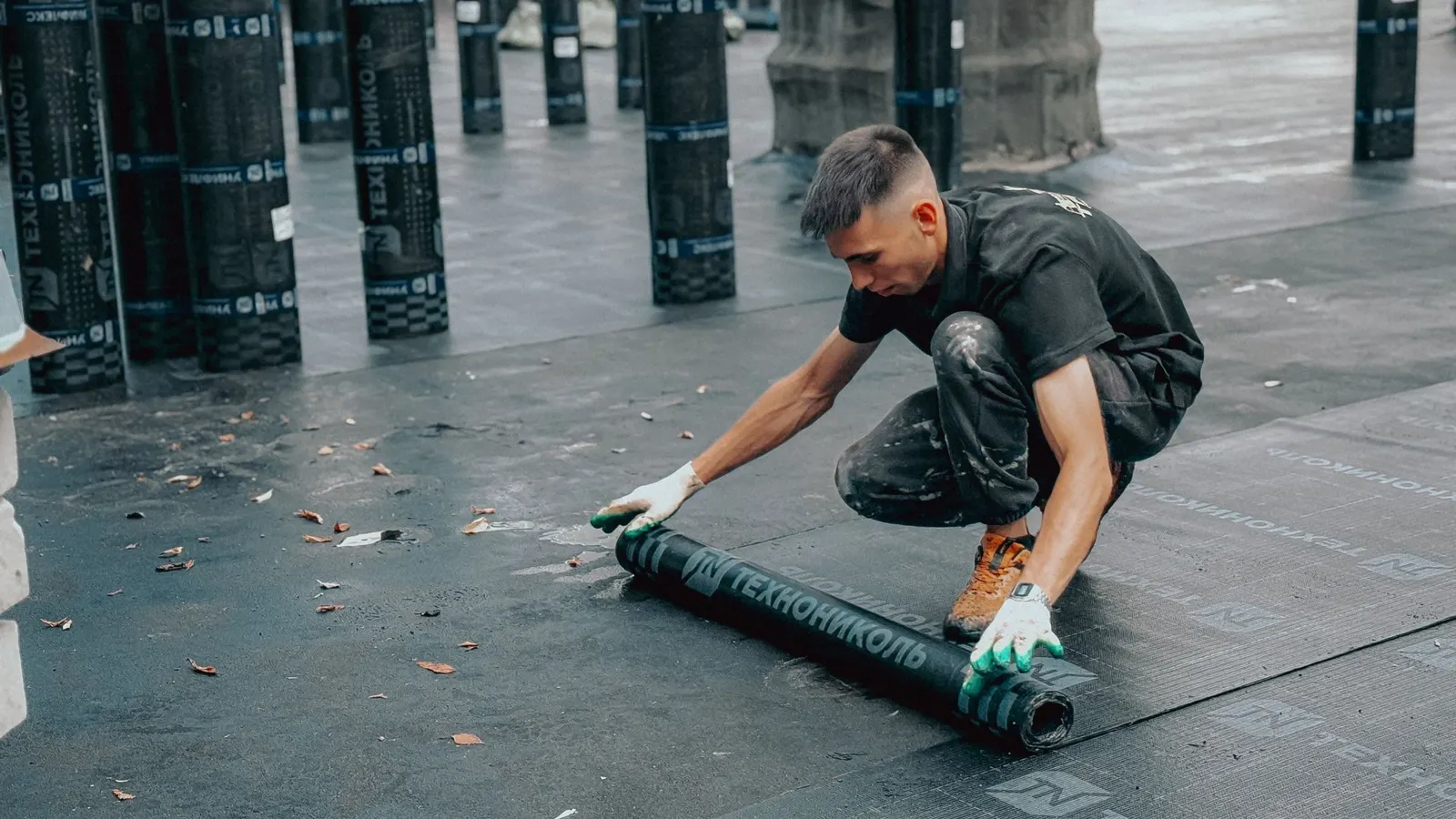 Roofer rolling out bitumen felt membrane on a flat roof