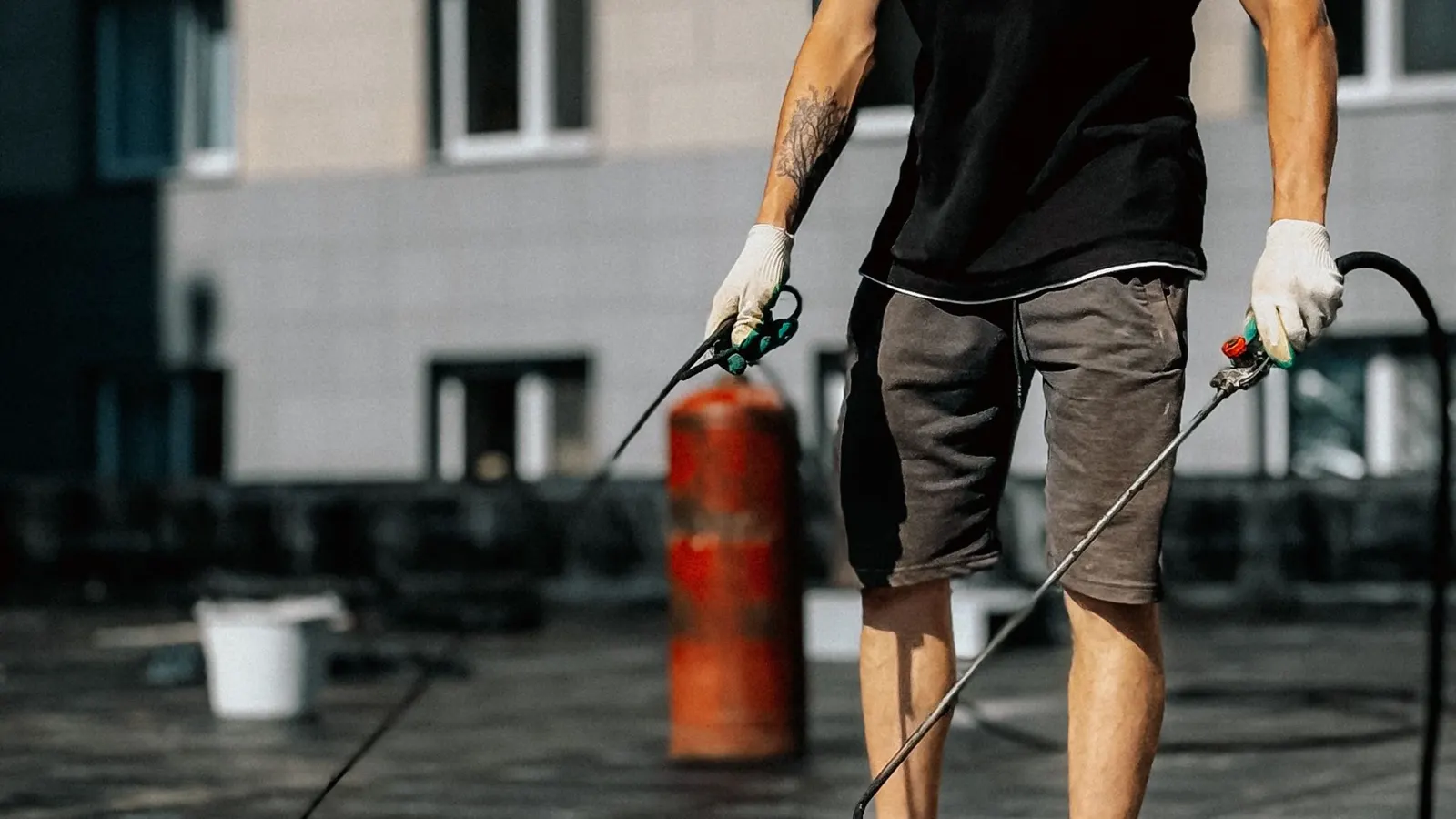 Roofer using a gas torch to apply torch-on felt to a flat roof
