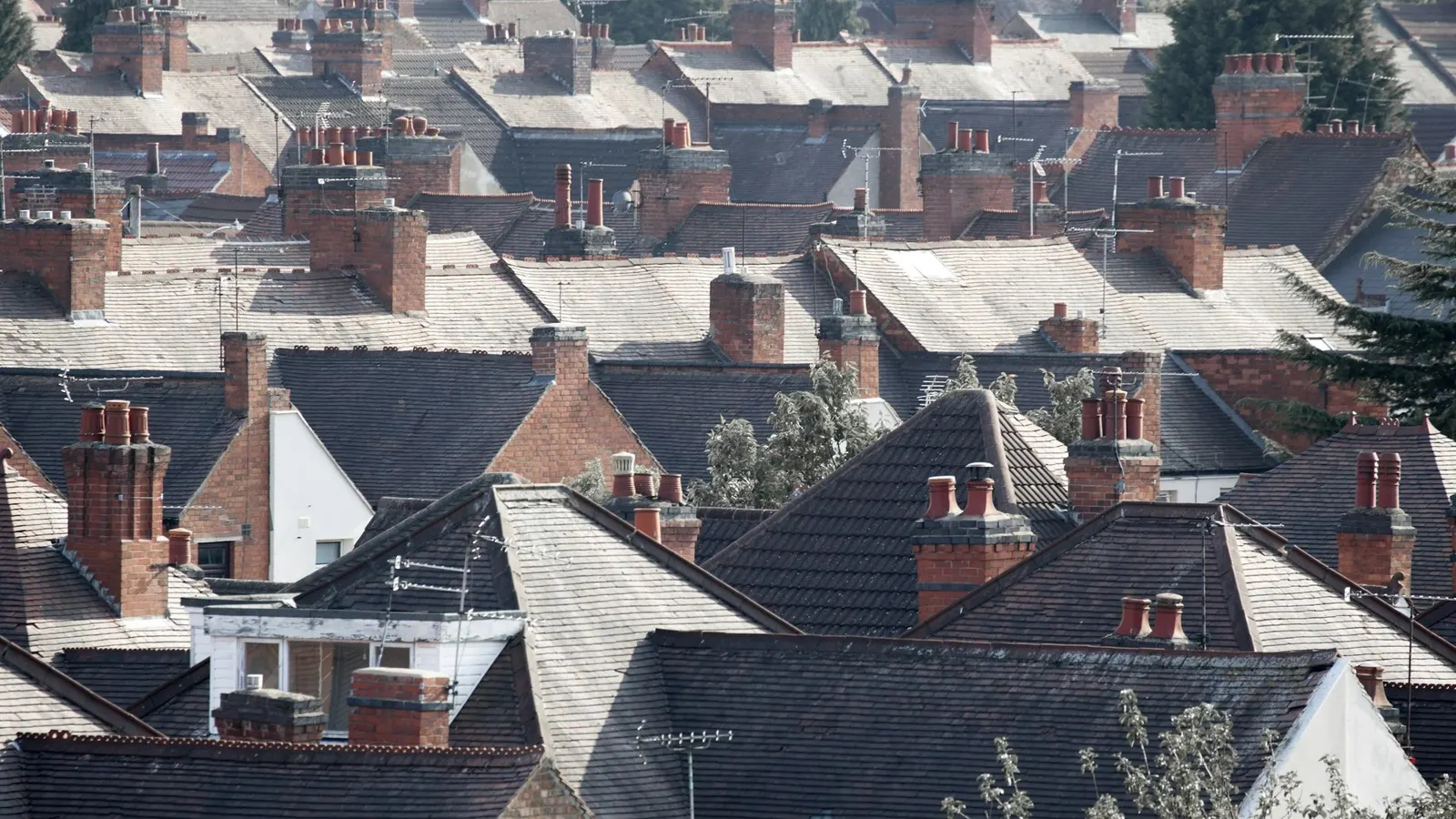 Aerial view over rows of British terraced house rooftops with slate roofs and brick chimney stacks
