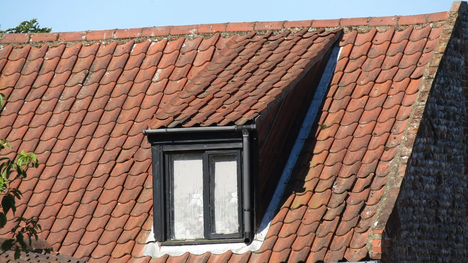 Dormer window set into a red clay tile roof with lead-weathered cheeks and flashing