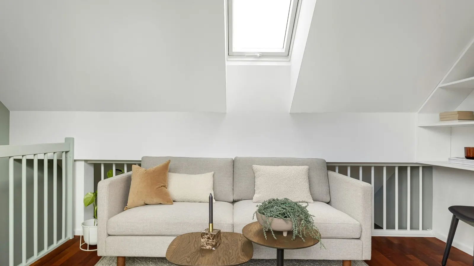 Light-filled loft room with Velux windows, sofa and stair balustrade