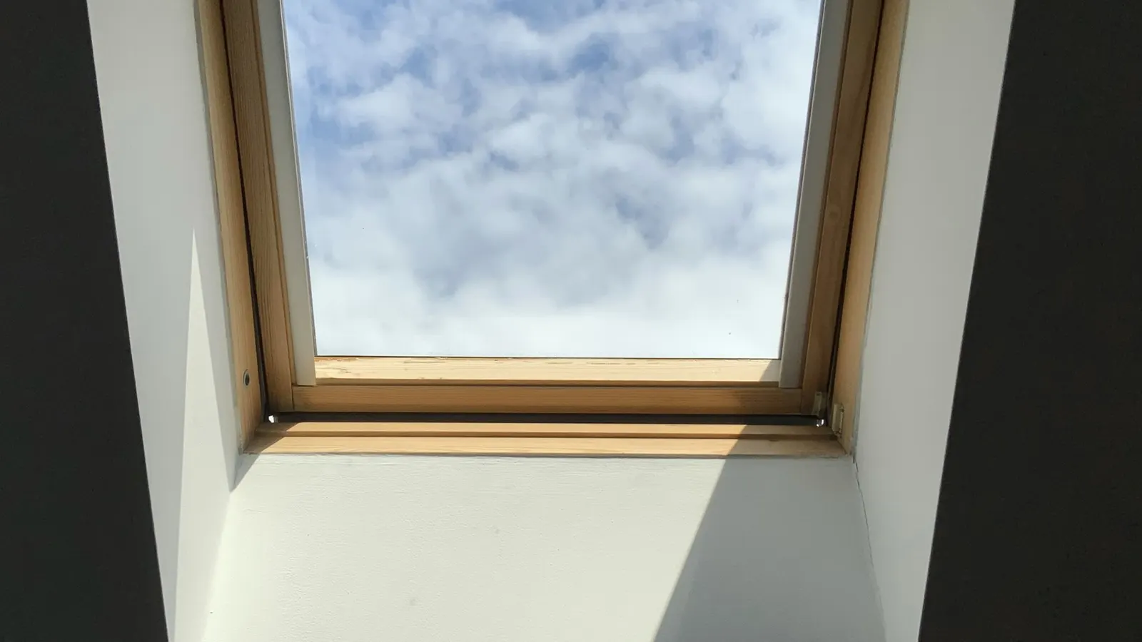 Looking up through a Velux roof window in a loft conversion to a blue sky