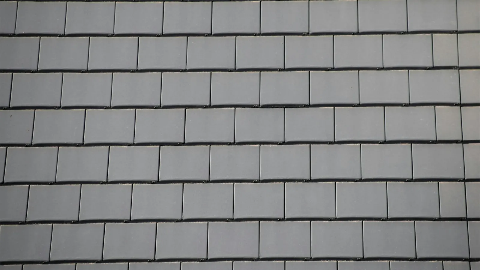 Neat courses of new grey slate tiles on a newly installed roof