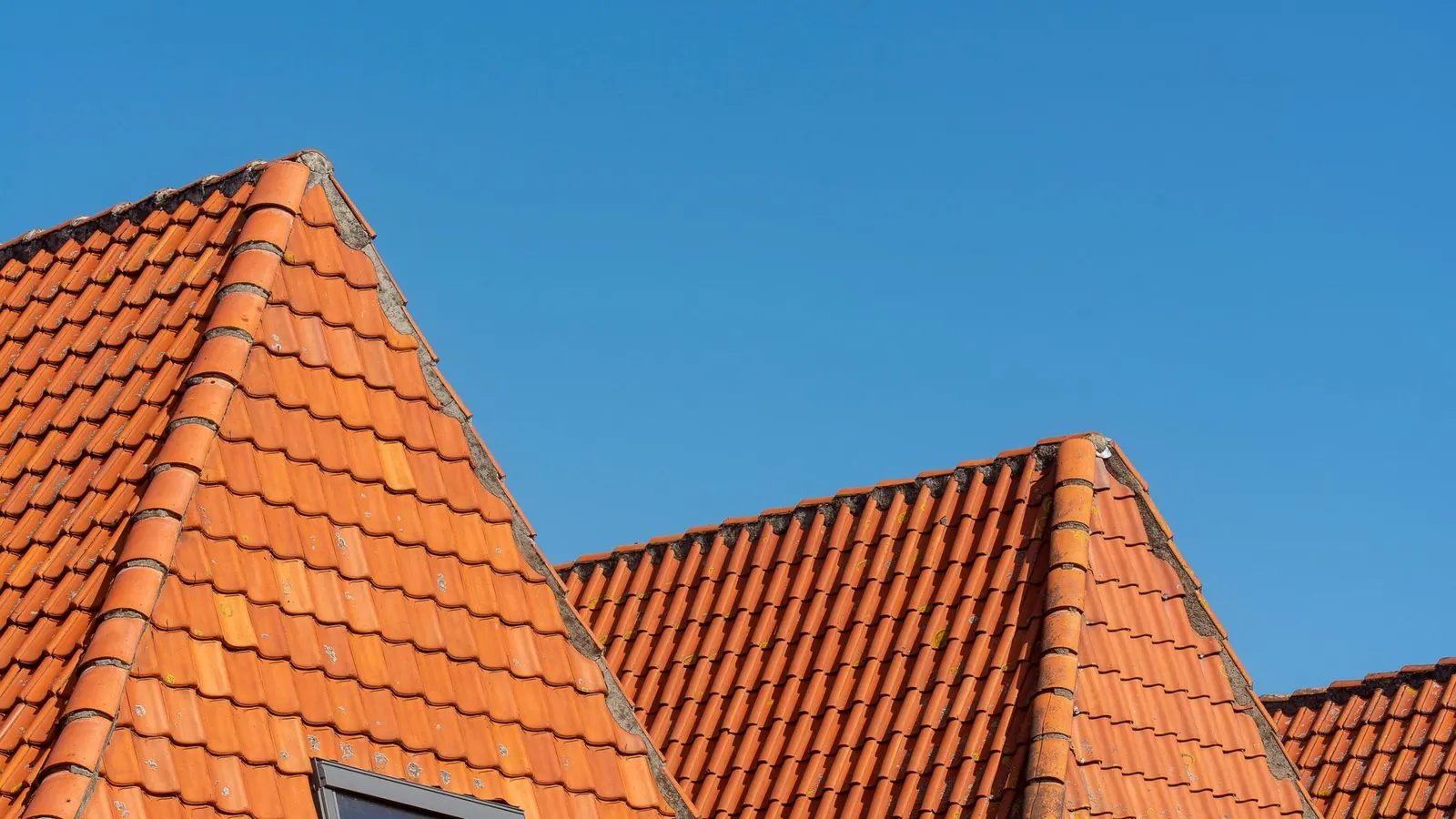 New orange clay tile roofs and gables against a clear blue sky