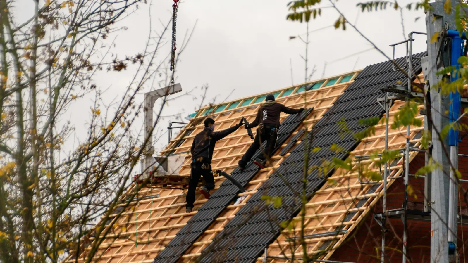 Roofing team stripping and re-covering a pitched roof, with new battens and tiles going on