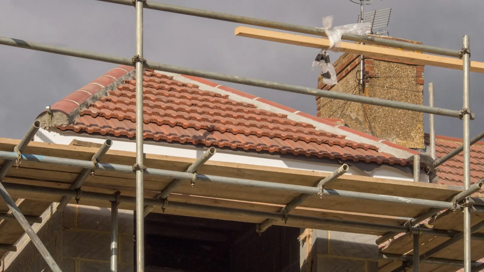 Scaffolding around the eaves of a clay tile roof during re-roofing