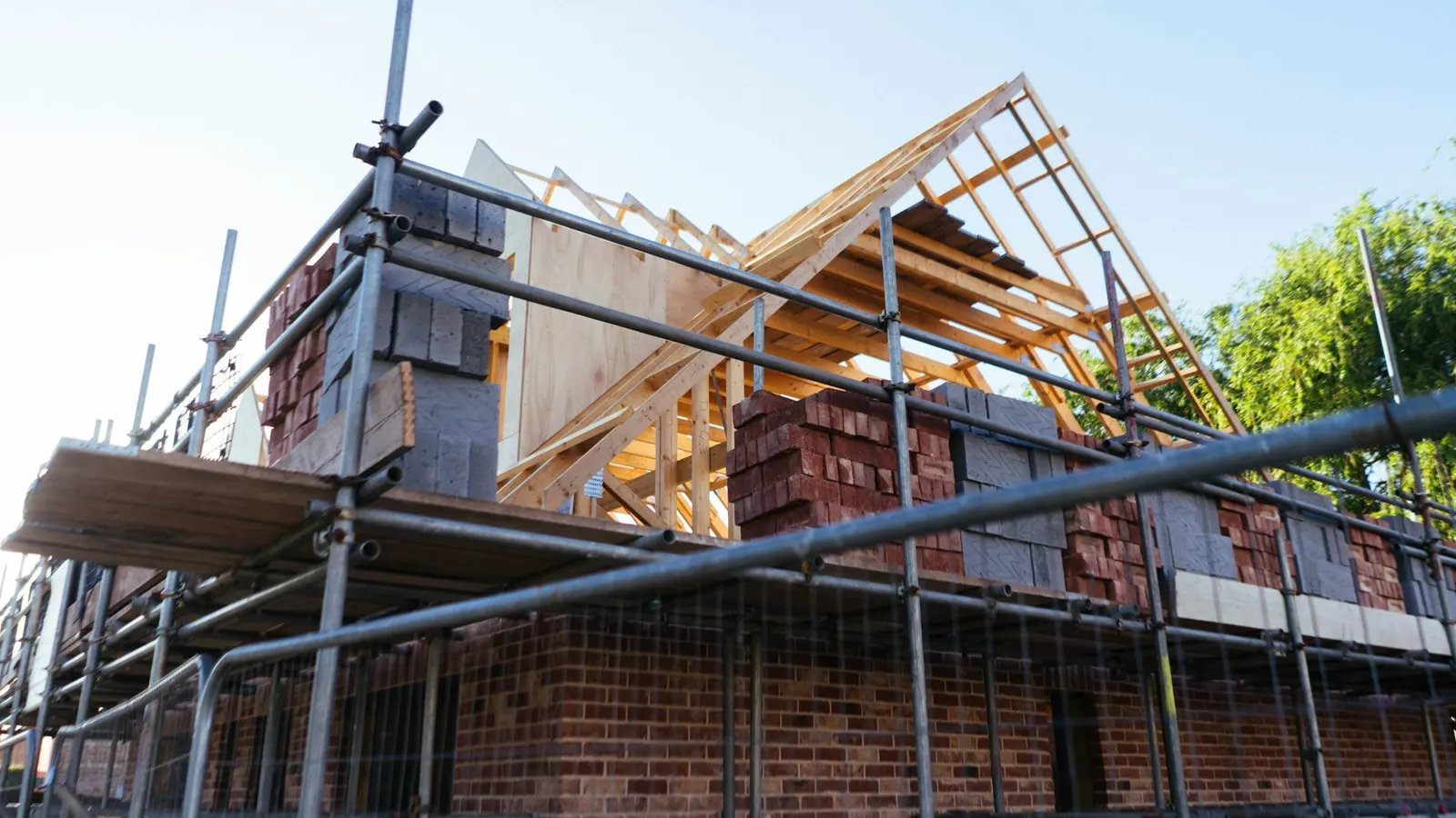 Brick house with full scaffolding and exposed roof timbers during re-roofing works